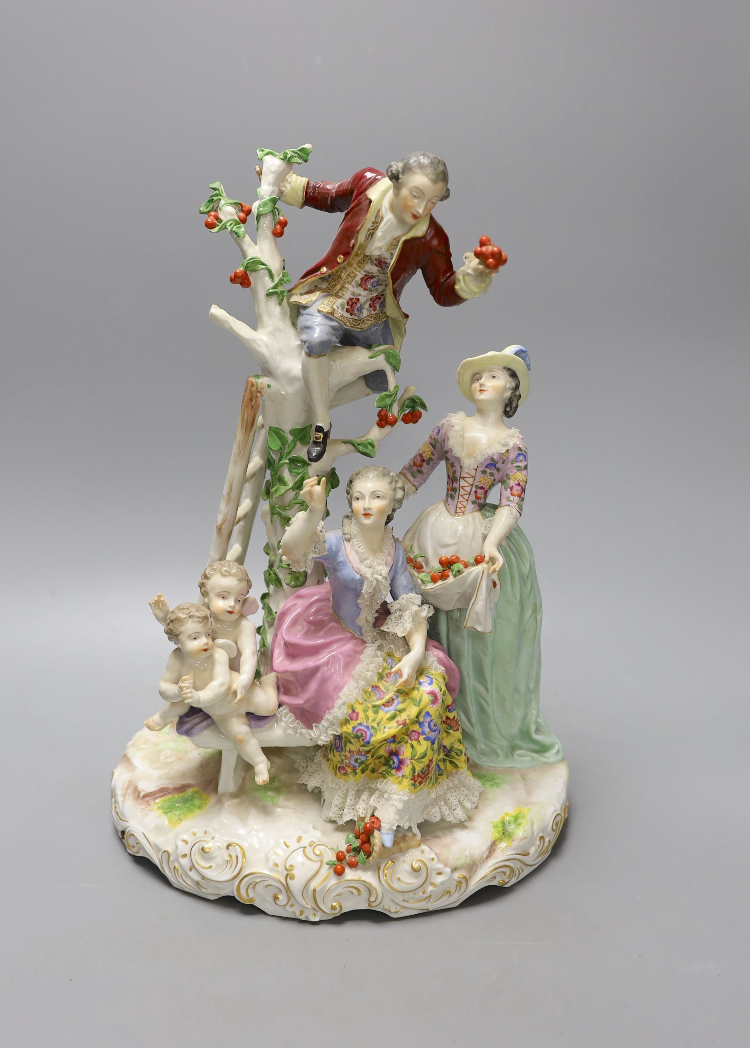 A large German porcelain group of figures picking fruit from a tree, 37cm